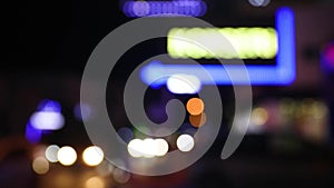 Cars, taxis driving and people walking on the night road. Colourful defocused flickering night Lights abstract background