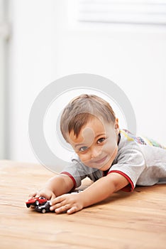 Cars, toys and portrait of child by table playing for learning, development and fun at modern home. Cute, sweet and boy