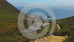 Cars turn a bend looking out to the Pacific Ocean in Big Sur, CA-1, California