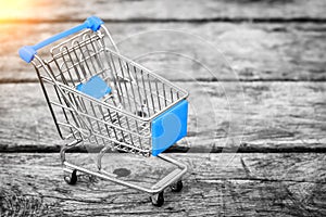 Cart from the grocery store on the old wooden background. Empty shopping trolley.