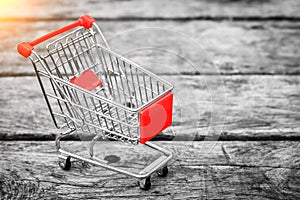 Cart from the grocery store on the old wooden background. Empty shopping trolley. Business ideas and retail trade.