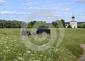 A cart with a horse rides through a meadow with the Church of the Pokrova-na-Nerl in Bogolyubovo village, Russia