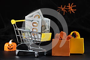 Cart with money hundred-dollar bills, paper bags for purchases. Halloween Sale