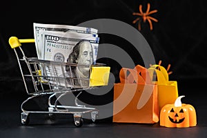 Cart with money hundred-dollar bills, paper bags for purchases. Halloween Sale