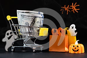 Cart with money hundred-dollar bills, paper bags for purchases. Halloween Sale