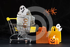 Cart with money hundred-dollar bills, paper bags for purchases. Halloween Sale