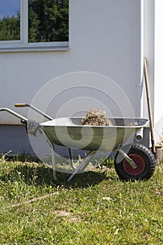A cart with soil next to the house. Excavation of earth around the house for the construction of a blind area.