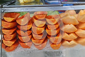 Cart Of Street Fruit Vendor With Sliced Papaya, Melon, Watermelon And Mango On Tray For Sale On The Street In Bangkok Night Market