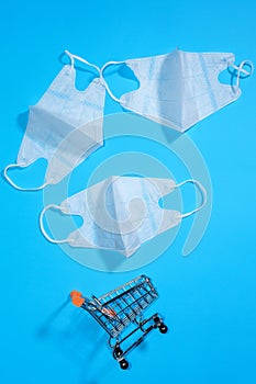 Cart and white medical masks on a blue background. Protection against viruses and infections. Prevention of diseases transmitted