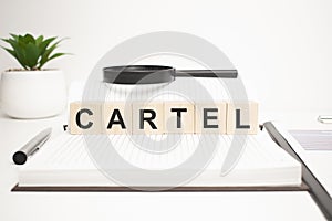 cartel word concept. wooden cubes, notepad, pen and business charts photo