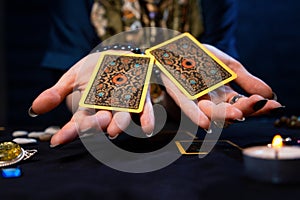 Cartomancy. The fortune teller holds out two Tarot cards on her palms. Close up. The concept of divination, astrology and photo