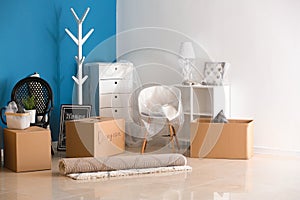 Carton boxes and interior items on floor in room. Moving house concept