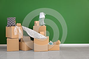 Carton boxes and interior items near color wall in room. Moving house concept