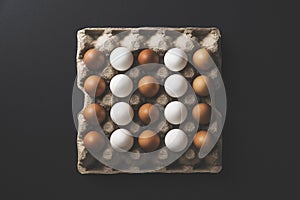Carton of white and brown chicken eggs on black background