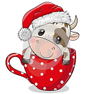 Cartoon Bull in a Santa hat is sitting in a Cup photo