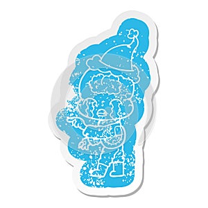 cartoon distressed sticker of a big brain alien crying and pointing wearing santa hat