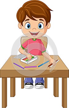 Cartoon little boy with pencils on the desk