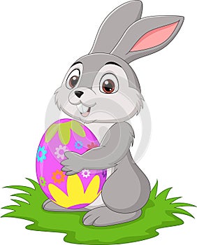 Cartoon little rabbit holding easter egg in the grass