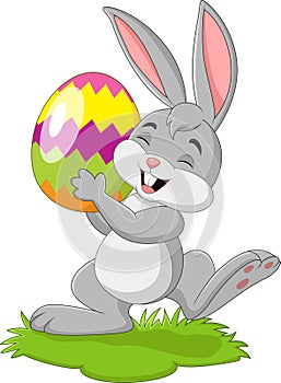 Cartoon little rabbit holding easter egg in the grass