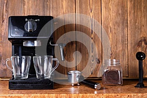 Cartridge coffee maker with manual cappuccino maker with two transparent mugs on a wooden table top background. Copy space for