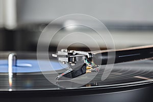 Cartridge on tonearm close up and blurred background for space for text.