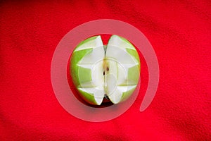 Carved apple on red background, close up / Green apple cut out decoratively / Fruits and vegetables healthy food