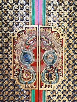 Carved and brightly painted mythological figure on the door, Bali