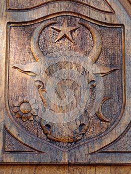 Carved bull on old, wooden door symbols of day, night, nature, Romania