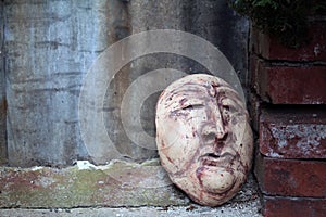 Carved Clay Face Leaning Against a Red Brick Wall