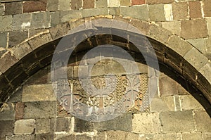 Carved crosses and patterns on the wall under the oval ledge above the entrance gate to the territory of Geghard Monastery in Arme