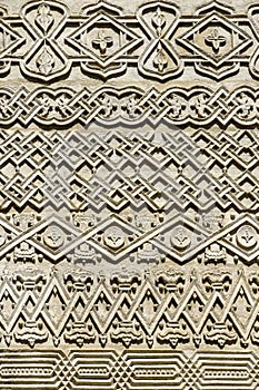 Carved embossed patterns on the stone wall of an ancient church building as a background. Fragment, detail.