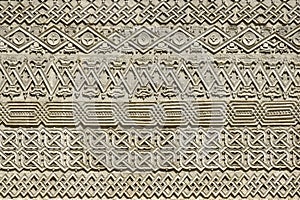 Carved embossed patterns on the stone wall of an ancient church building as a background. Fragment, detail.