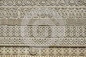 Carved embossed patterns on the stone wall of an ancient church building as a background. Fragment, detail.