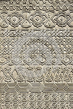 Carved embossed patterns on the stone wall of an ancient church building as a background. Fragment, detail.