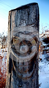 Carved face on a tree trunk disturbing smile