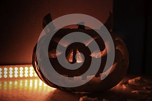 Carved halloween pumpkin with horns and red backlight on the background