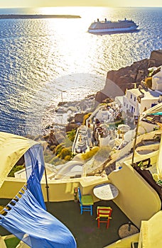 Carved houses terrace and cruise ship passing Oia Santorini Greece