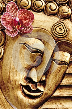 Carved image of Buddha with orchid blossom