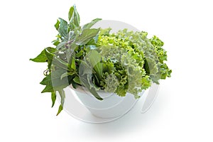 Carved lettuce, coriander and basil leaves arranged on a plate.