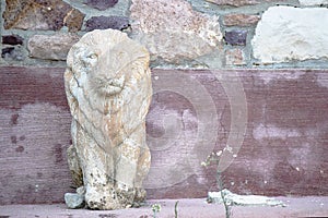 Carved lion statue on the roadside. Patterned wall behind