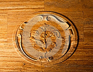 Carved round wooden motif with flowers and scrolls on panel