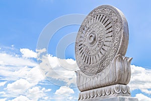 Carved sandstone Dharmachakra on blue sky background