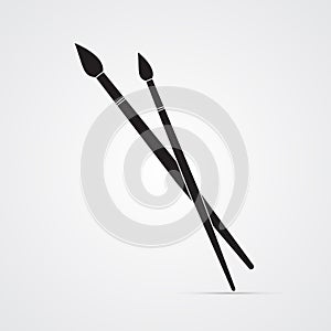 Carved silhouette flat icon, simple vector design. Two crossed paintbrushes. Artist`s brushes