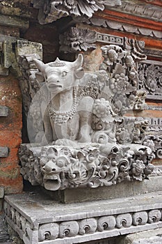 Carved stone bull atop a fierce smiling gargoyle at a temple in Bali Indonesia