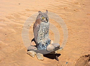 A carved wooden owl perched on sand in utah`s desert