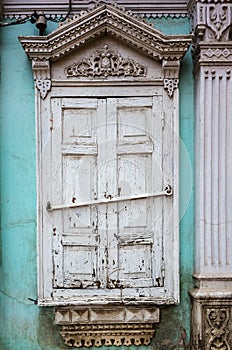 Carved wooden window with platbands and closed shutters, a fragment of the facade of an old building