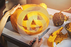 Carving pumpkin into jack-o-lantern for halloween holiday decoration at home kitchen