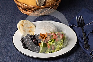 Casado, typical Costa Rican dish with rice, beans and vegetables in white plate