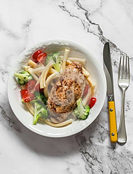 Casarecce pasta with broccoli, cherry tomatoes and baked chicken breast on a light background, top view
