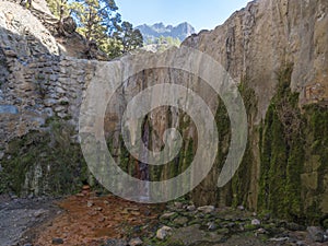 Cascada de Colores small allmost dry waterfall in a volcanic crater at Caldera de Taburiente, water stream is colorful